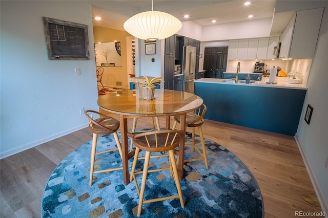 dining area featuring baseboards, wood finished floors, and recessed lighting