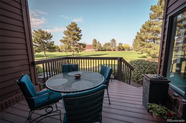 wooden deck with central air condition unit, a lawn, and outdoor dining space