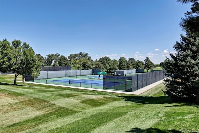 view of tennis court featuring a lawn and fence