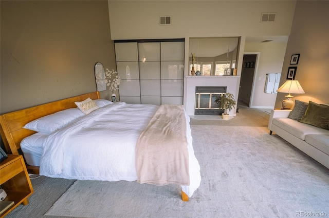 carpeted bedroom featuring a glass covered fireplace and visible vents