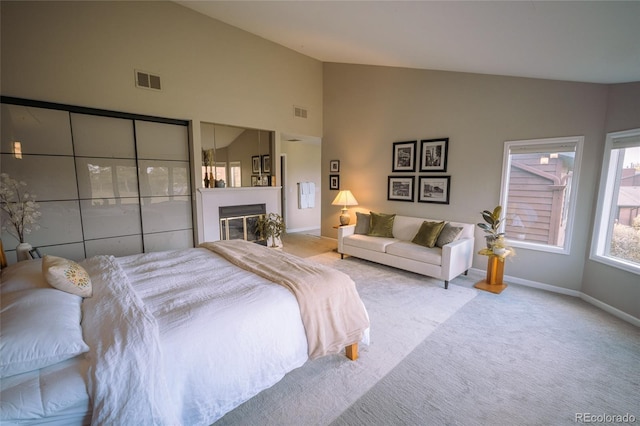 bedroom featuring carpet floors, a glass covered fireplace, visible vents, and baseboards