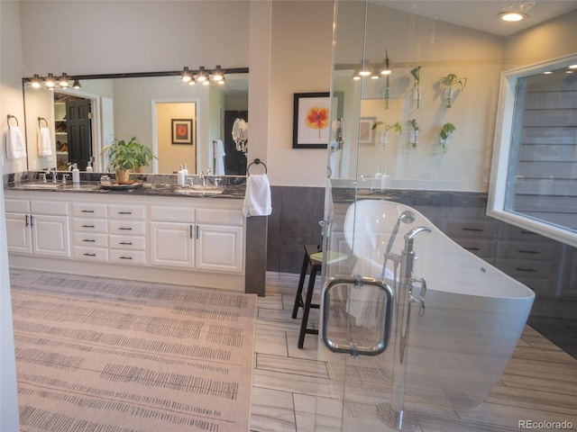 full bath featuring lofted ceiling, a freestanding bath, a sink, and double vanity