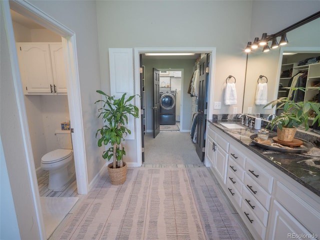 bathroom with toilet, baseboards, washer / clothes dryer, and vanity