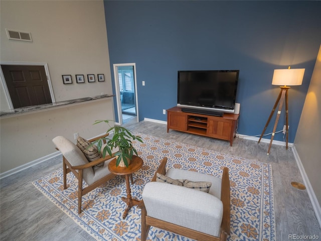 living area featuring light wood-style floors, visible vents, and baseboards