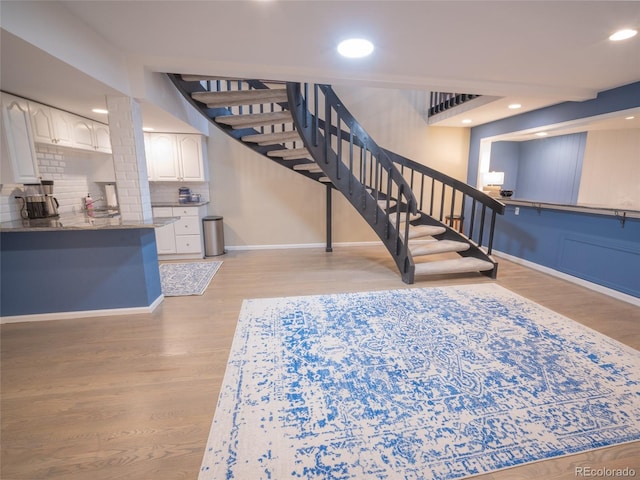 stairs featuring baseboards, wood finished floors, and recessed lighting