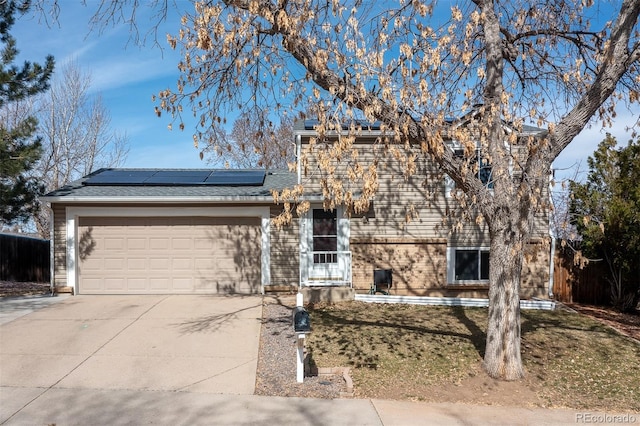 view of front of property featuring roof mounted solar panels, an attached garage, and driveway