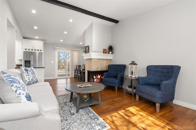 living room featuring light wood finished floors, baseboards, a tiled fireplace, lofted ceiling with beams, and recessed lighting