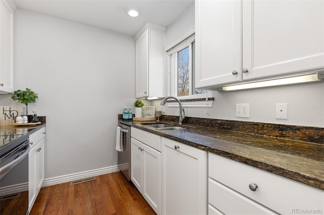 kitchen with a sink, dark stone countertops, dark wood finished floors, white cabinetry, and dishwasher