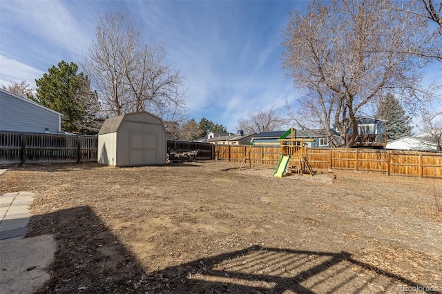 view of yard featuring a playground, an outbuilding, a fenced backyard, and a shed