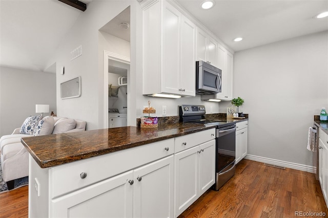 kitchen featuring recessed lighting, washer / dryer, white cabinets, stainless steel appliances, and dark wood-style flooring