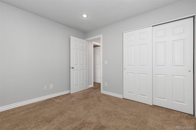 unfurnished bedroom with baseboards, carpet floors, and a closet