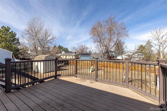 wooden terrace featuring a residential view, an outbuilding, and a storage shed