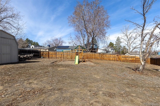 view of yard featuring an outbuilding, a fenced backyard, a shed, and a playground