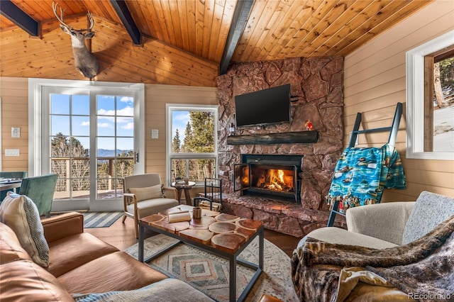 living area with wooden walls, wood ceiling, a stone fireplace, and wood finished floors
