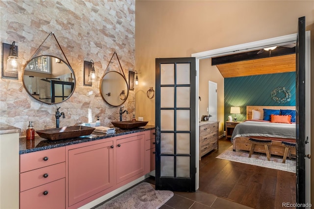 ensuite bathroom with an accent wall, double vanity, and tile patterned floors