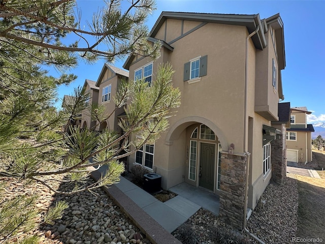 10835 Tincup Creek Pt, Colorado Springs, CO 80908 - rear view of property with stucco siding, stone siding, and central AC unit
