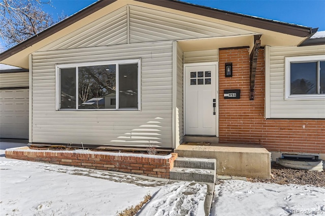 snow covered property entrance with a garage