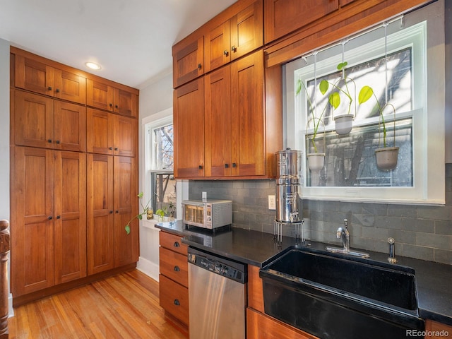 kitchen with decorative backsplash, sink, dishwasher, and light hardwood / wood-style floors