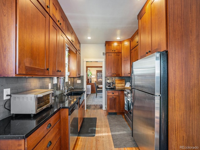 kitchen featuring appliances with stainless steel finishes, light hardwood / wood-style floors, backsplash, and sink