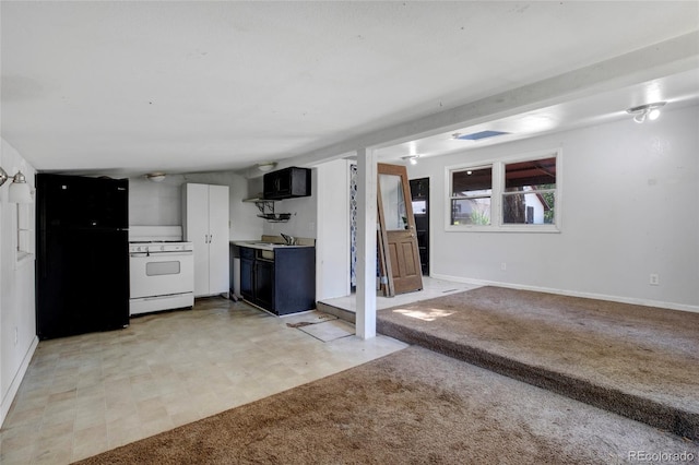 kitchen with light tile patterned flooring, white cabinetry, black fridge, white stove, and sink