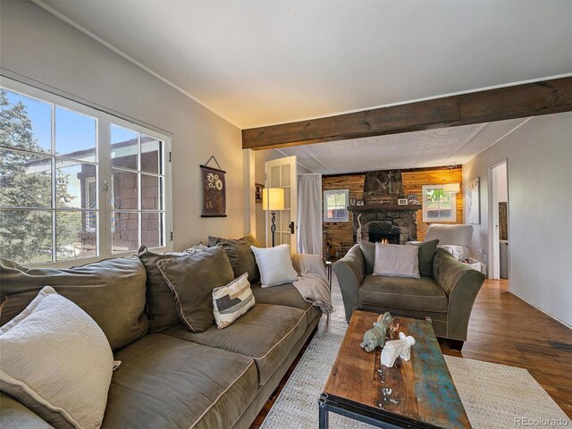 27385 Spruce Ln, Evergreen, CO 80439 - living room with wood finished floors, beam ceiling, wooden walls, and a stone fireplace