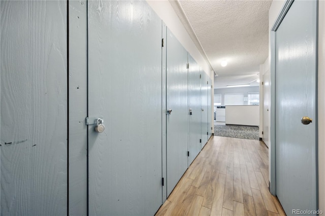 hall with a textured ceiling and light hardwood / wood-style flooring