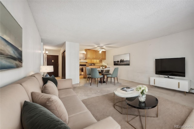 carpeted living room featuring ceiling fan and a textured ceiling