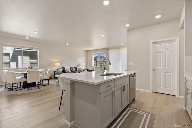 6150 Sugarloaf St, Brighton, CO 80601 - kitchen featuring light wood-type flooring, light countertops, open floor plan, dishwasher, and a kitchen island with sink