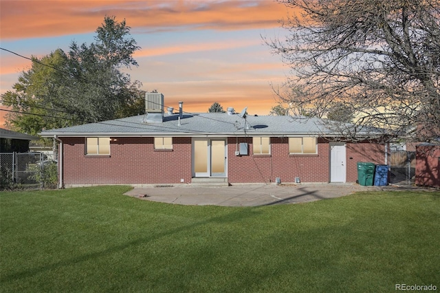 back house at dusk with a patio and a yard