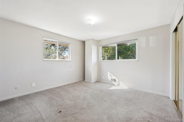 empty room with light colored carpet and a healthy amount of sunlight