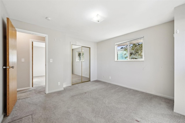 unfurnished bedroom with light carpet and a closet