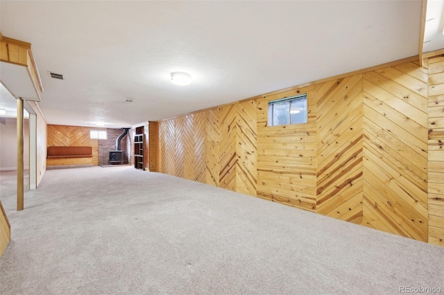 basement featuring a wood stove, carpet, and wooden walls