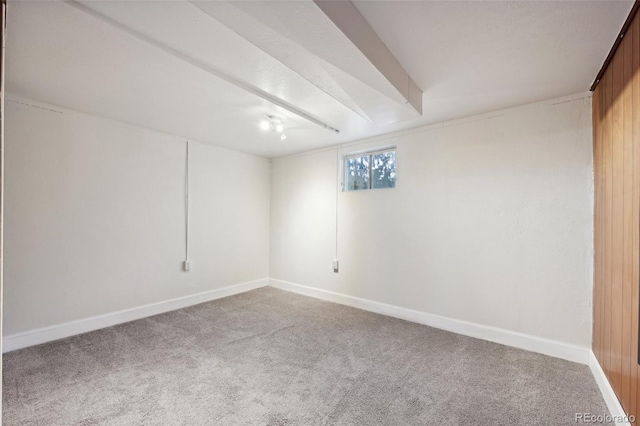 carpeted spare room with wood walls and beam ceiling