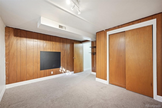 interior space featuring wooden walls, track lighting, and light carpet