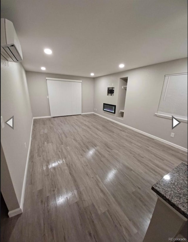 basement with a wall unit AC and wood-type flooring