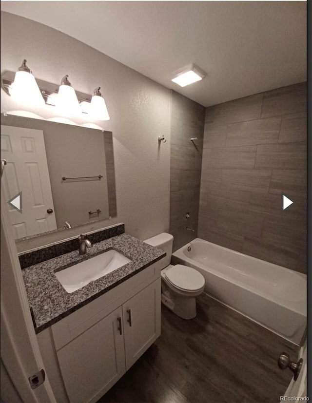 full bathroom with toilet, vanity, hardwood / wood-style floors, and tiled shower / bath