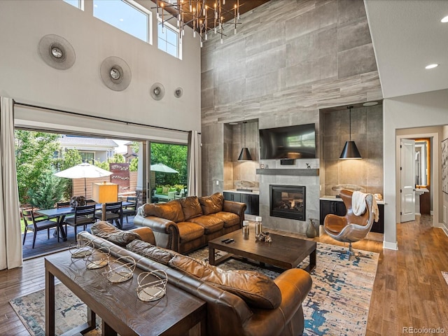 1291 Fountain Ln, Erie, CO 80516 - living room with a high ceiling, a tiled fireplace, wood-type flooring, and a chandelier