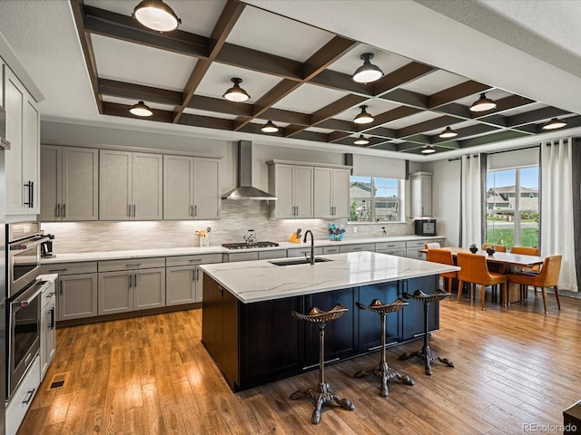 1291 Fountain Ln, Erie, CO 80516 - kitchen featuring wall chimney exhaust hood, coffered ceiling, stainless steel appliances, tasteful backsplash, and light stone countertops