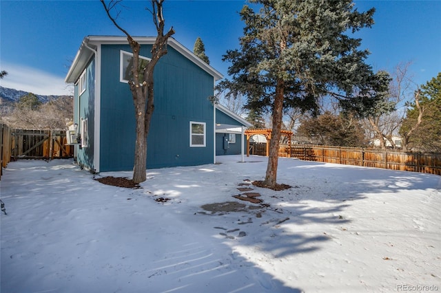 snow covered rear of property featuring a mountain view and a pergola