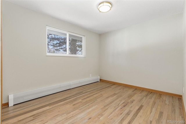 spare room featuring baseboard heating, baseboards, and wood finished floors