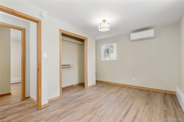 unfurnished bedroom with a closet, light wood-style floors, baseboards, and a wall mounted air conditioner