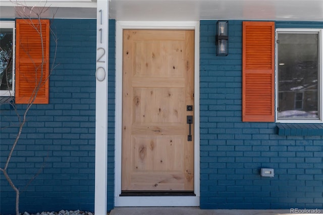 doorway to property featuring brick siding