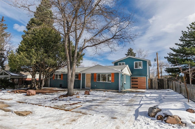 view of front facade with an attached garage, driveway, and fence