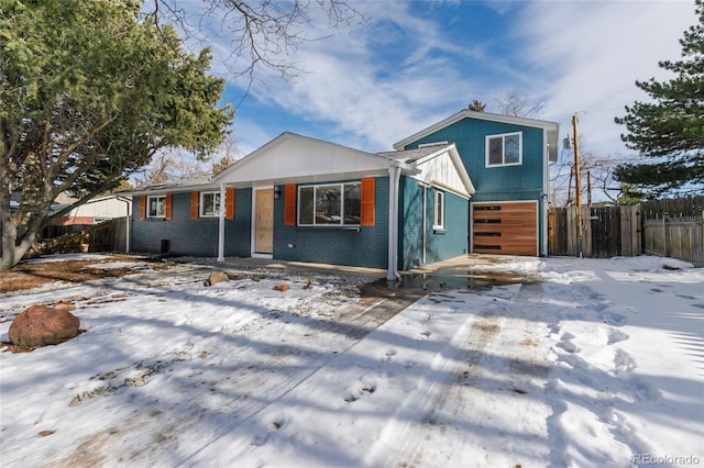 view of front of house featuring a garage, fence, and brick siding