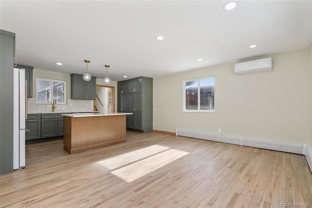 kitchen featuring freestanding refrigerator, a sink, light countertops, light wood-style floors, and a wall mounted air conditioner