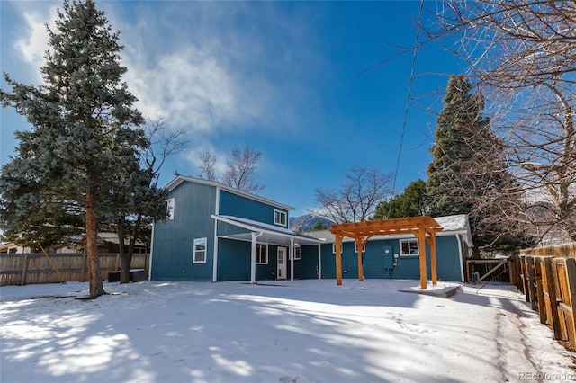 snow covered rear of property with a pergola and a fenced backyard