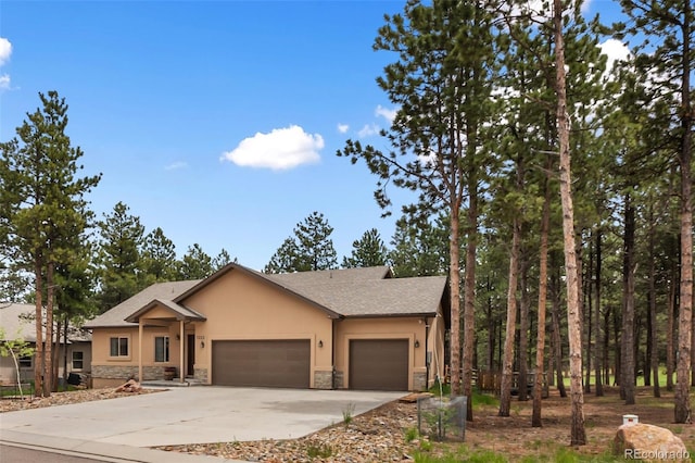 1323 Firestone Dr, Woodland Park, CO 80863 - view of front of home featuring stone siding, stucco siding, an attached garage, and driveway