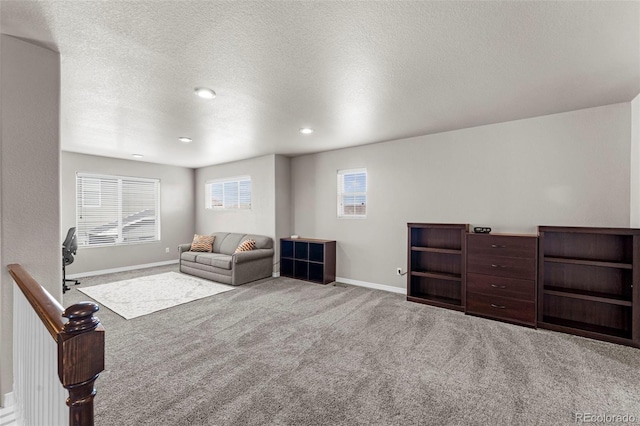 living area featuring carpet, baseboards, and a textured ceiling