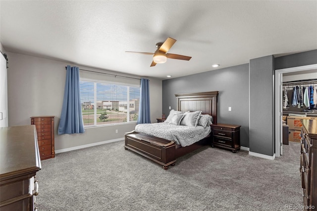 bedroom with light carpet, a walk in closet, and baseboards