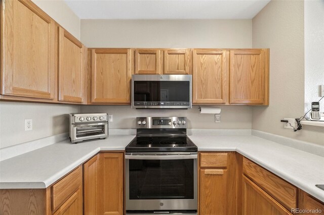 228 Quari St, Aurora, CO 80011 - kitchen featuring appliances with stainless steel finishes, light countertops, and light brown cabinets